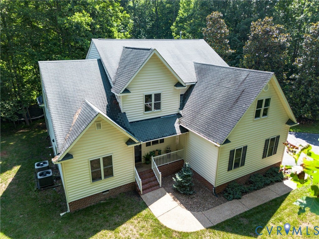 Traditional-style home featuring light yellow siding, dark-shingle roofing, and multiple gables