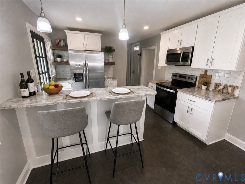 White shaker cabinetry, stainless steel appliances, light-toned countertops, white subway tile backsplash, and dark wood-finish flooring