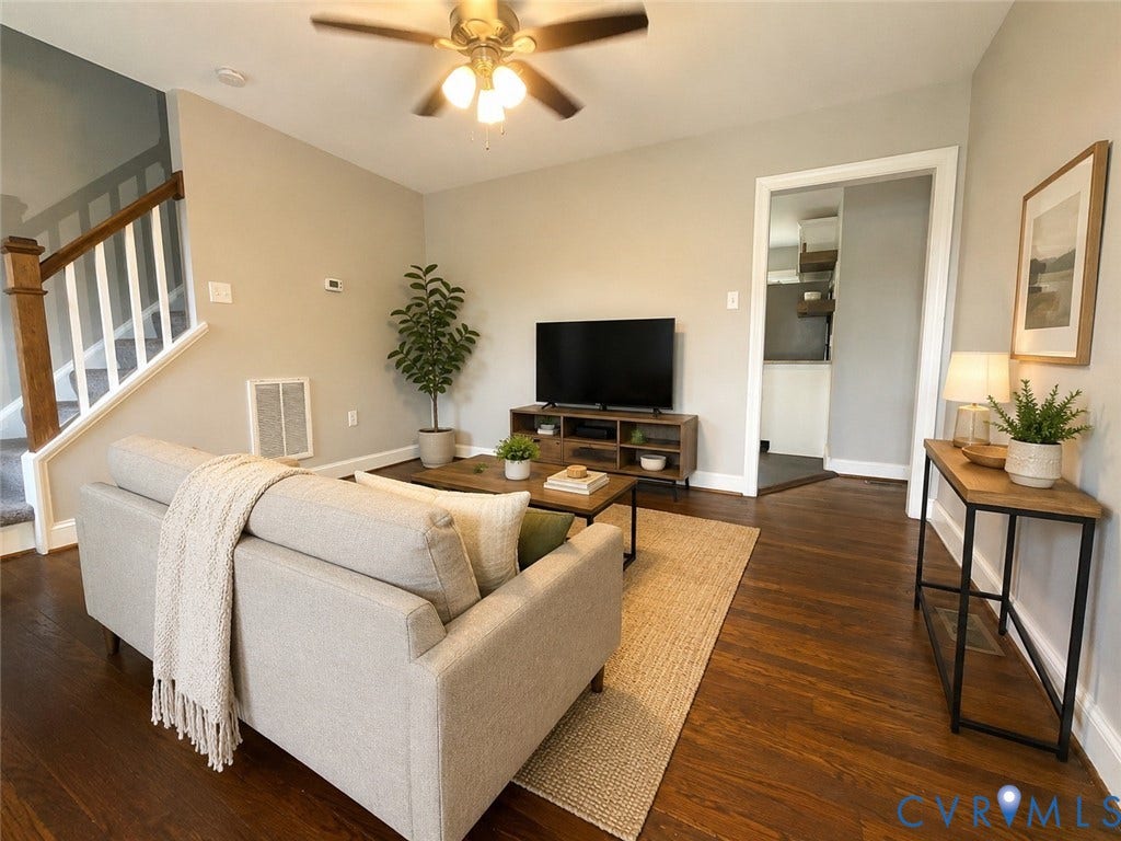 Wood-finish flooring, staircase with wood handrail and white spindles, ceiling fan, and painted walls