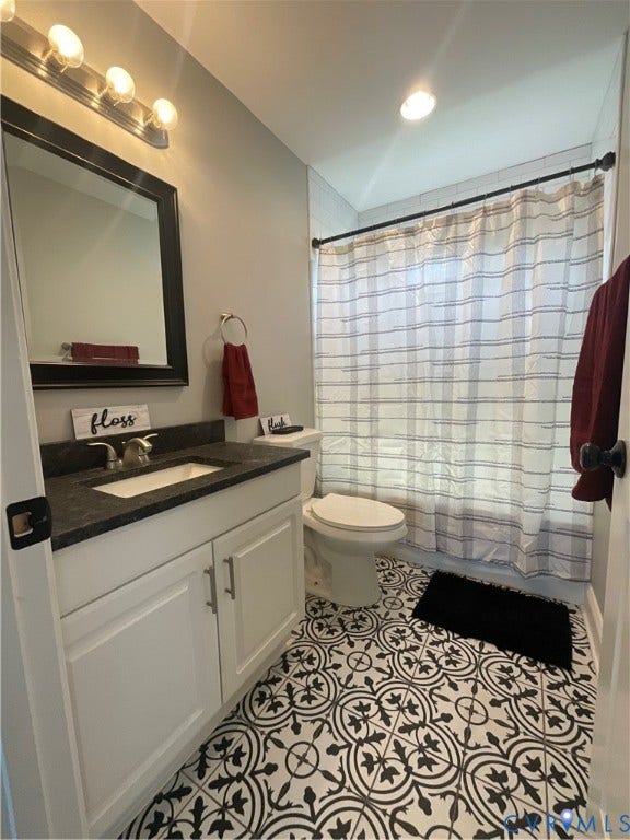 White shaker-style vanity with brushed nickel hardware and dark countertop
