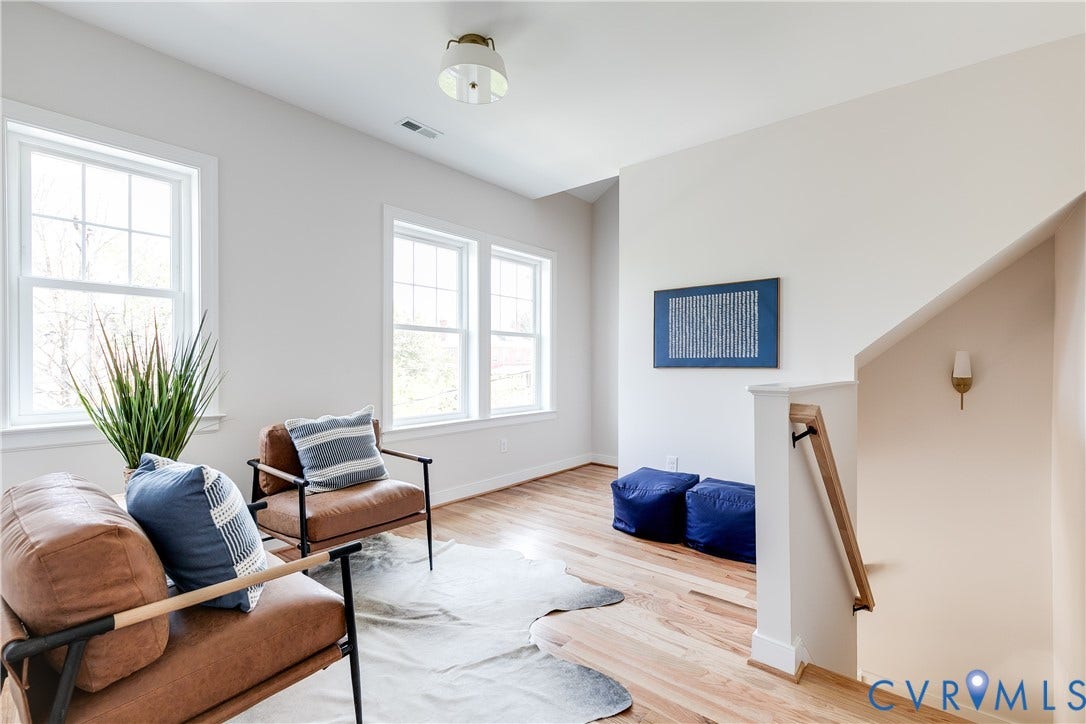 404 W 31st Street, Woodland Heights, Richmond, VA 23225 Hardwood flooring, multiple windows, contemporary ceiling light fixture, wall-mounted sconce, and a wood handrail