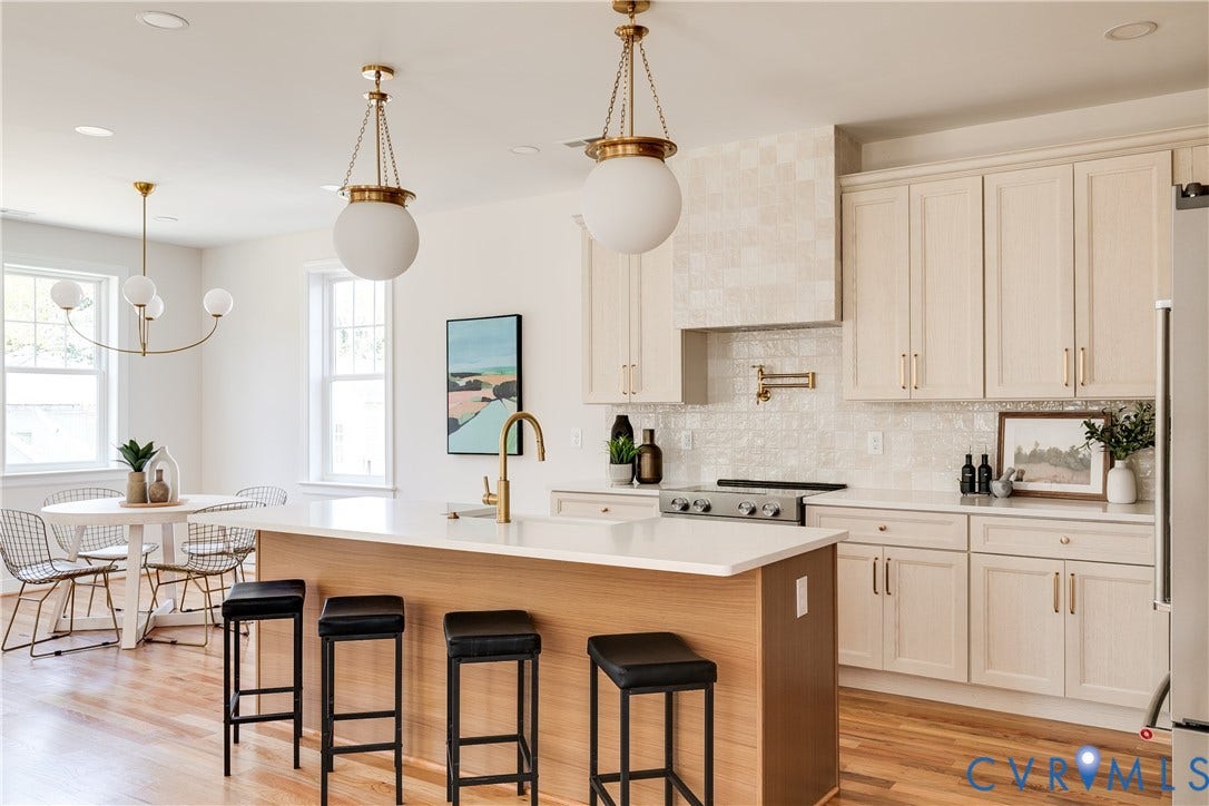 404 W 31st Street, Woodland Heights, Richmond, VA 23225 Open-concept kitchen with light wood-finish cabinetry, a large central island with seating, a gas range with a pot filler, and light wood-finish flooring