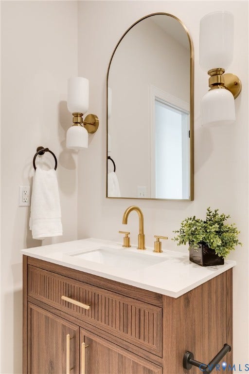 404 W 31st Street, Woodland Heights, Richmond, VA 23225 Vanity with a white countertop and integrated sink, gold-finish faucet, and wood-finish cabinetry