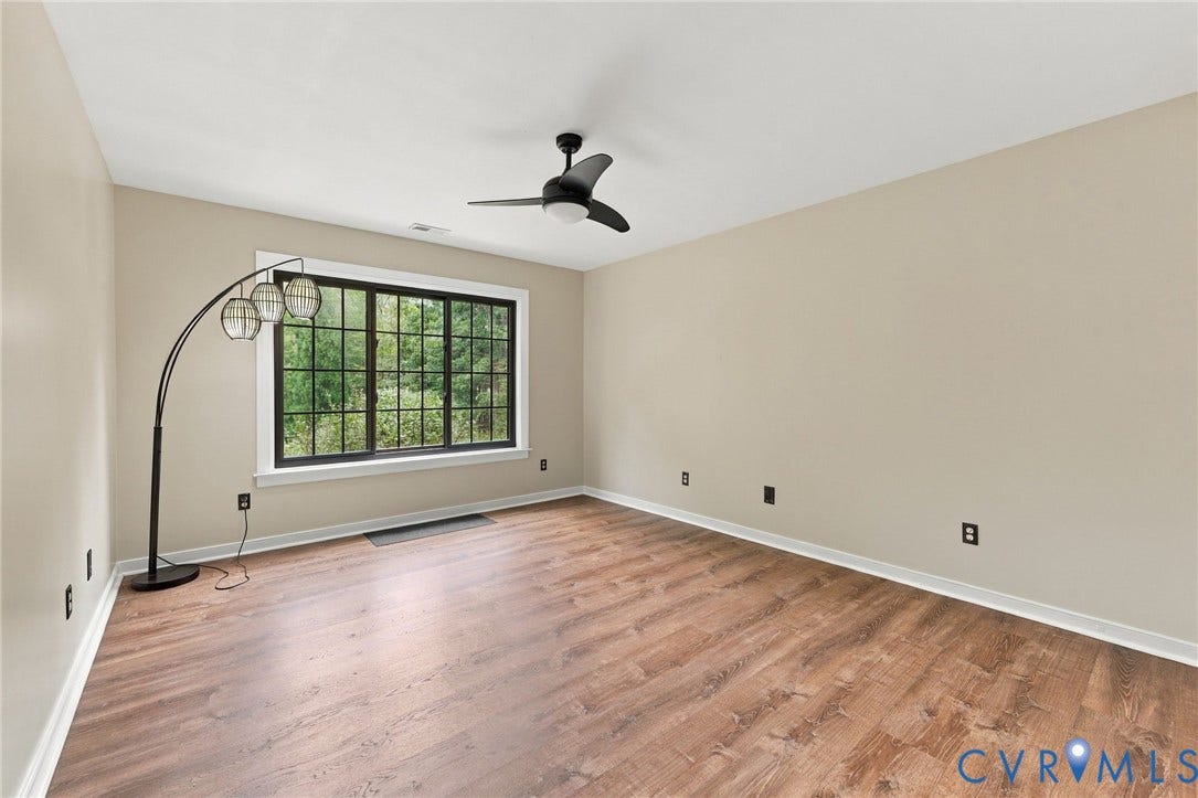 133 Ford Road, Bumpass, VA 23024 Wood-finish flooring, large window with black framing, ceiling fan, and neutral wall tones