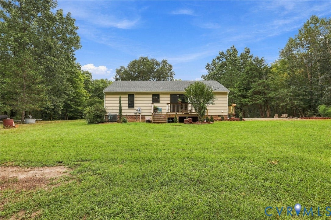 133 Ford Road, Bumpass, VA 23024 Expansive rear yard featuring green lawn, mature trees, and a raised wooden deck