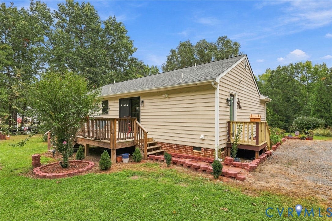 133 Ford Road, Bumpass, VA 23024 Exterior siding, wood deck, brick foundation, gravel driveway, and mature trees