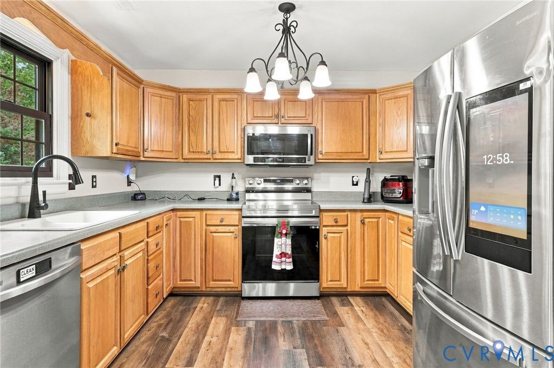 133 Ford Road, Bumpass, VA 23024 Kitchen featuring wood cabinetry, stainless steel appliances, a built-in sink, wood-finish flooring, and a window