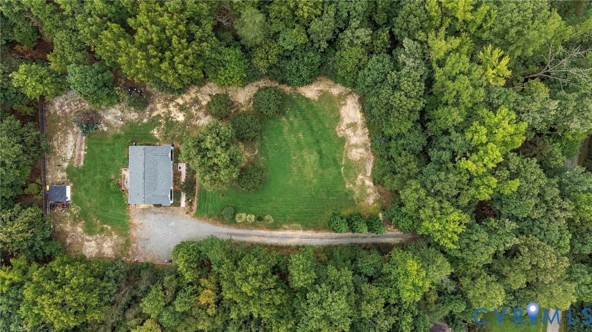 133 Ford Road, Bumpass, VA 23024 Expansive lot surrounded by mature trees, featuring a gravel driveway, a manicured lawn, and a shingled roof home
