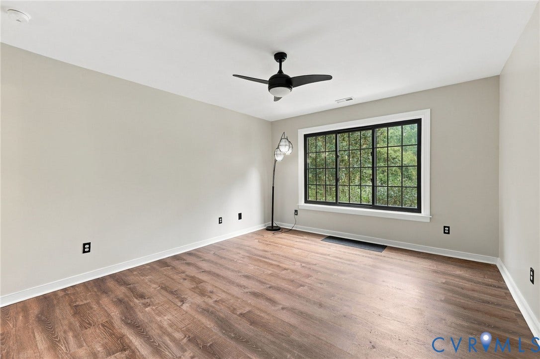133 Ford Road, Bumpass, VA 23024 Expansive room featuring wood-finish flooring, a large multi-pane window, a ceiling fan with integrated lighting, and neutral wall tones