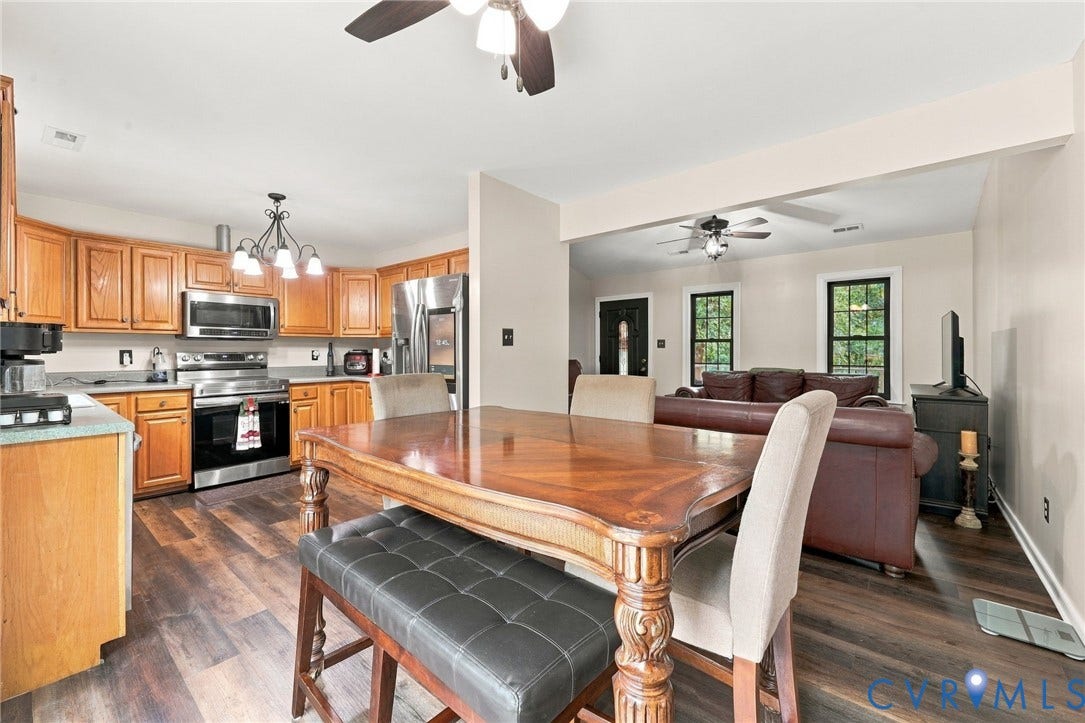 133 Ford Road, Bumpass, VA 23024 Wood-finish flooring throughout, kitchen featuring wood cabinetry and stainless steel appliances, and a ceiling fan with integrated lighting