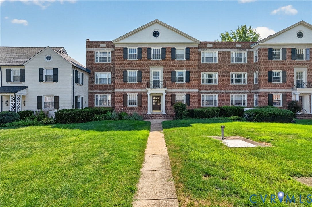 Brick building exterior with multiple levels, white trim, and dark shutters