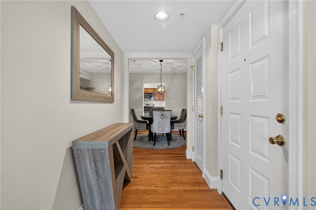 Panel door entry with brass hardware, wood-finish flooring, and recessed lighting