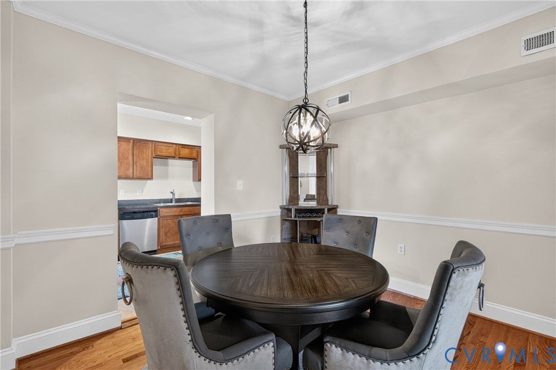 Hardwood flooring, crown molding, chair rail molding, and an overhead orb chandelier