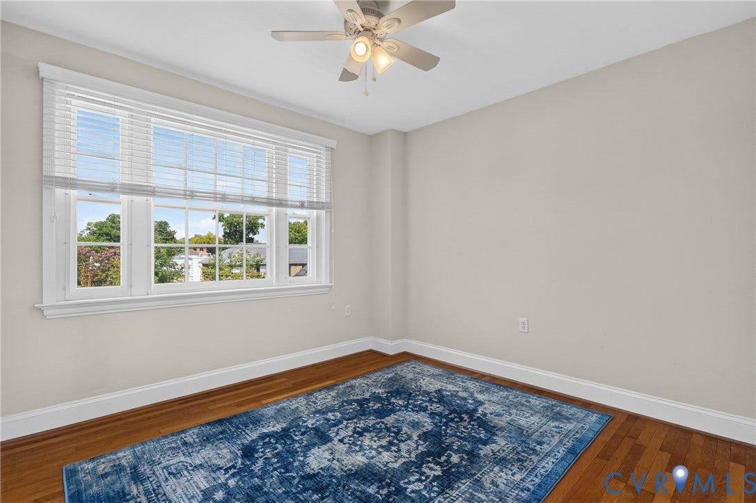 Hardwood flooring, multi-paned window with horizontal blinds, ceiling fan with integrated lighting, and neutral wall paint