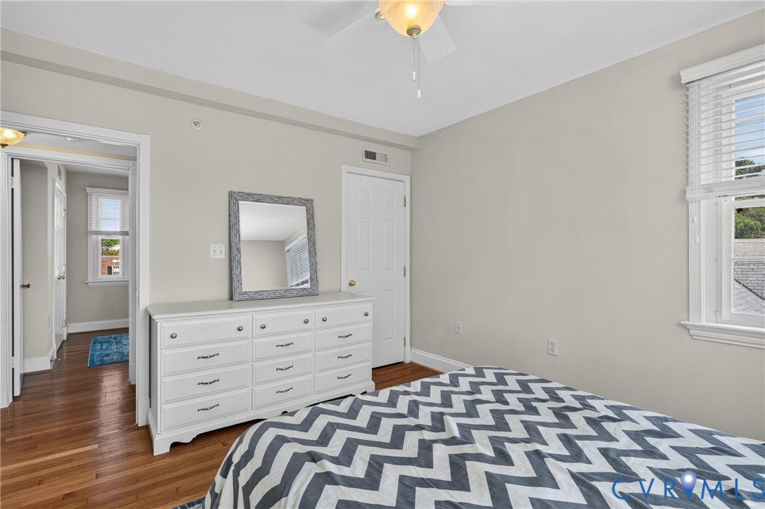 Hardwood flooring, light-toned walls, ceiling fan with integrated lighting, window with blinds, and white interior doors
