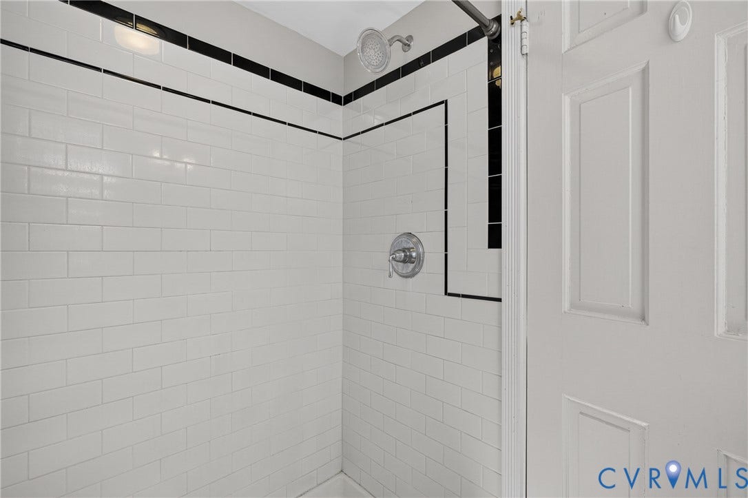 Subway tile shower surround with black accent trim and chrome fixtures