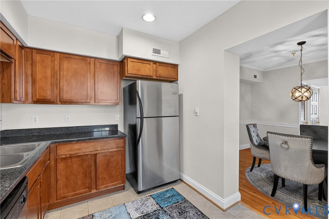 Kitchen featuring wood cabinetry, dark countertops, stainless steel refrigerator, and recessed lighting