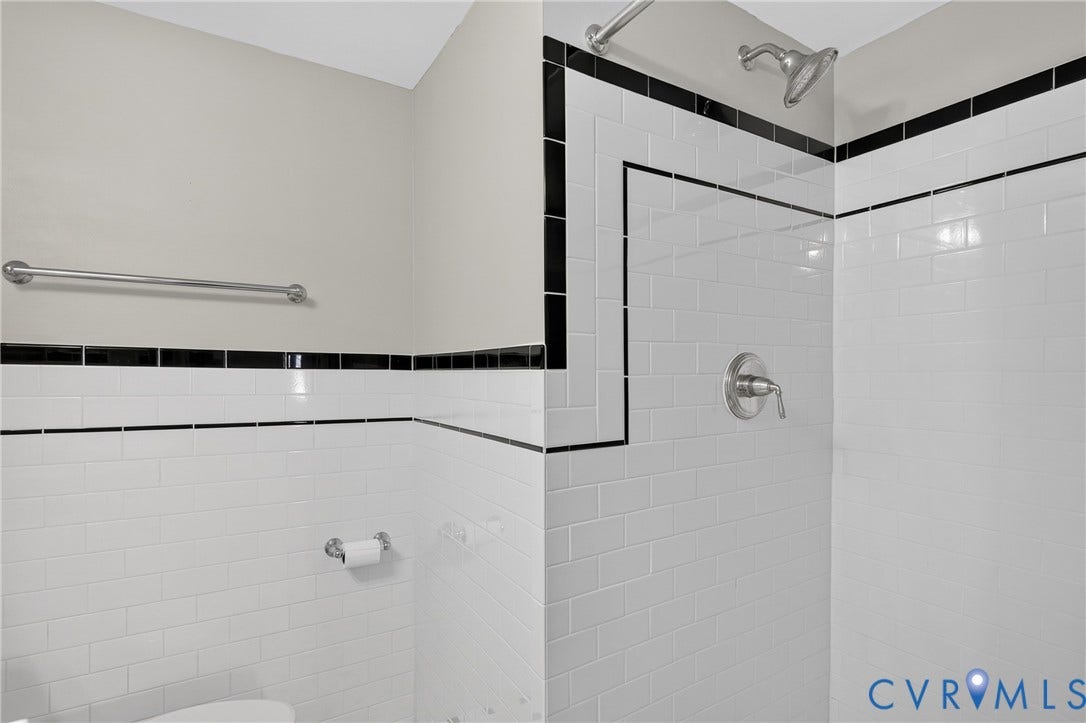 White subway tile surround with black accent trim and a polished chrome showerhead