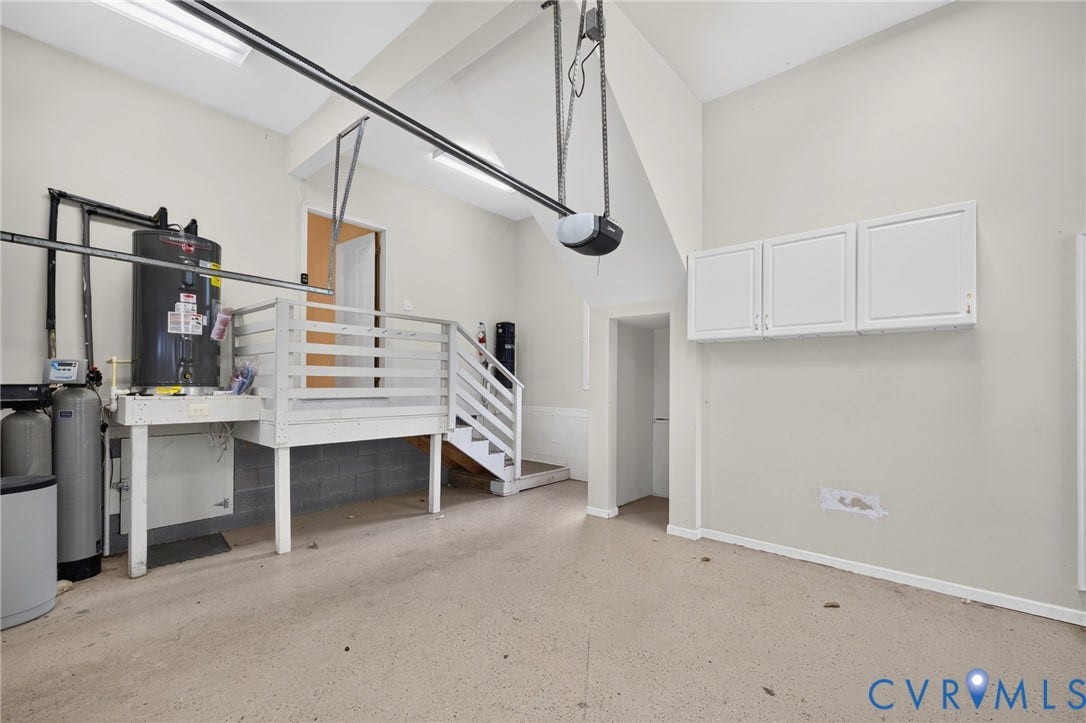 365 Hamlet Road, Manakin Sabot, VA 23103 Garage space featuring an epoxy-coated floor, overhead fluorescent lighting, built-in storage cabinets, a utility platform, and a water heater