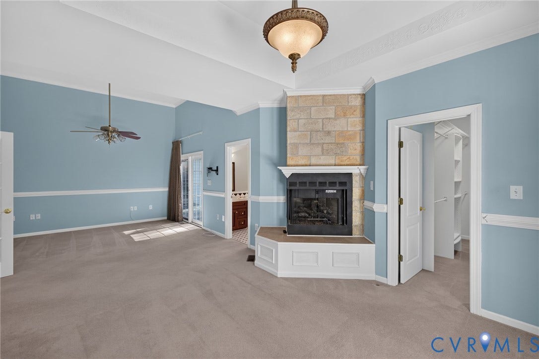 365 Hamlet Road, Manakin Sabot, VA 23103 Corner fireplace with a stone surround and white mantel, vaulted ceiling with a decorative ceiling fan and chandelier, and a walk-in closet with built-in shelving