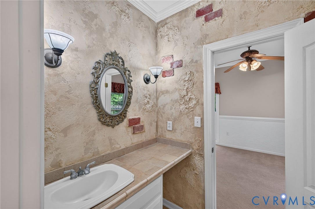 365 Hamlet Road, Manakin Sabot, VA 23103 Textured wall finish with brick accents, vanity with integrated sink, tile countertop, and decorative wall sconces