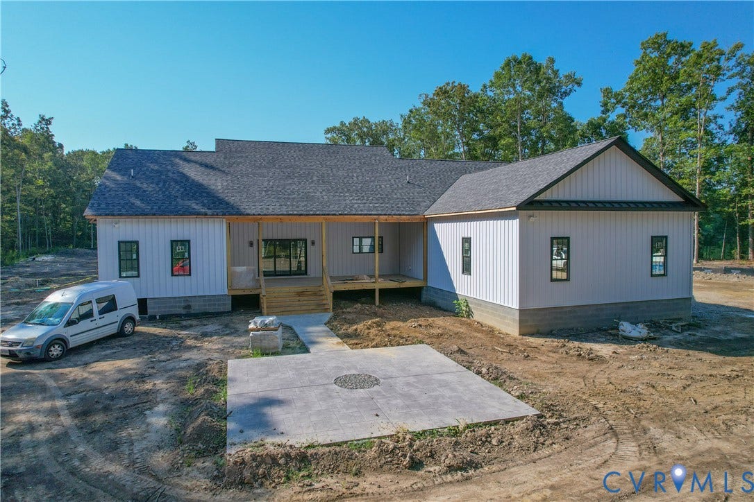 13216 Bradley Bridge Road, Chester, VA 23831 Board-and-batten siding with dark trim, asphalt shingle roofing, and a concrete patio
