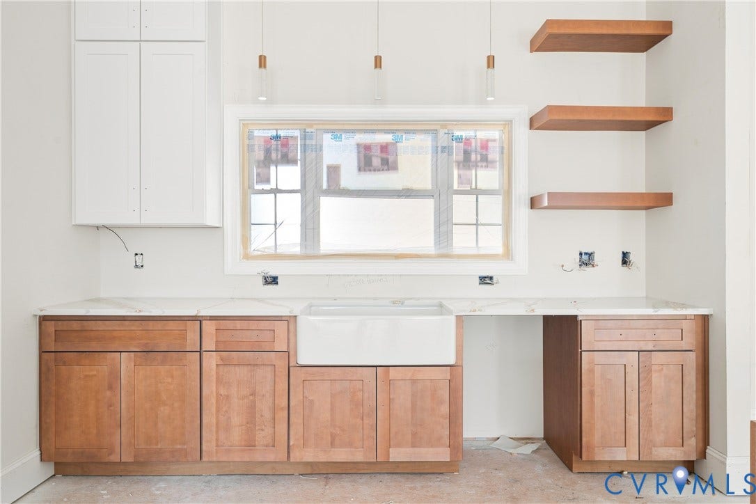 13216 Bradley Bridge Road, Chester, VA 23831 White upper cabinetry, wood-finish lower cabinetry, farmhouse-style sink, light-toned countertops, and open wood-finish shelving