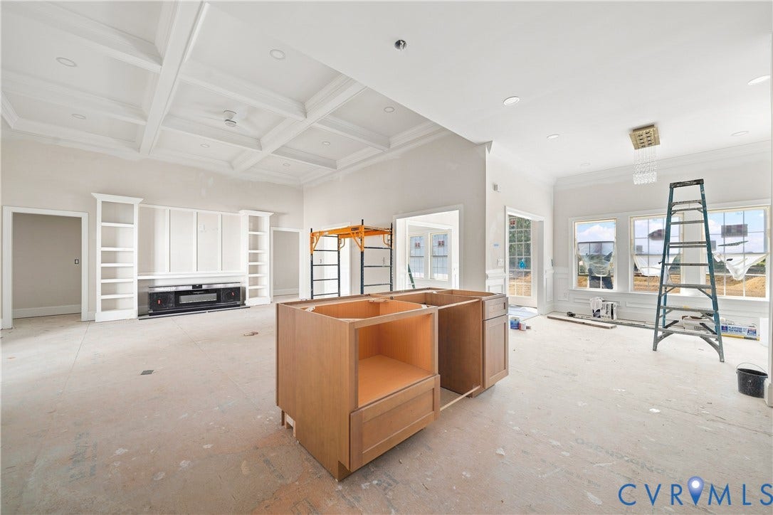 13216 Bradley Bridge Road, Chester, VA 23831 Coffered ceiling with recessed lighting, built-in entertainment center with shelving, multiple large windows, and a partially installed kitchen island