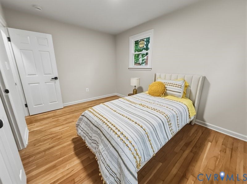 Hardwood flooring, neutral wall tones, white trim, and a paneled door with matte black hardware