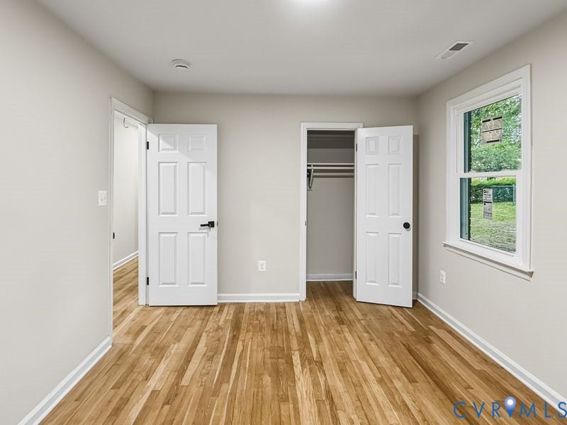 Hardwood flooring, light gray walls, white trim, recessed lighting, and a closet with bifold doors