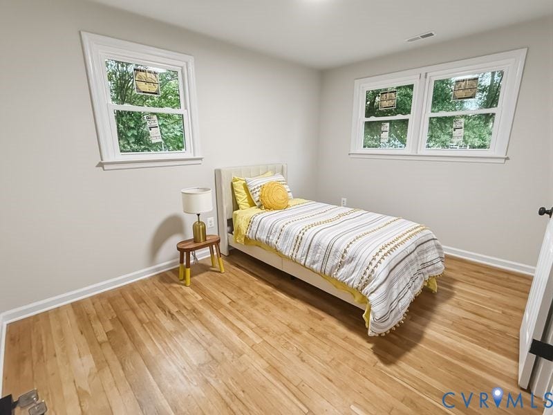 Light-toned wood flooring, white trim, and two windows