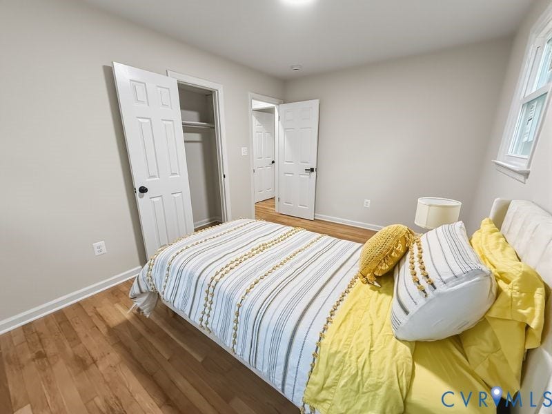 Wood-finish flooring, white paneled doors, ceiling-mounted lighting, and a window with white trim