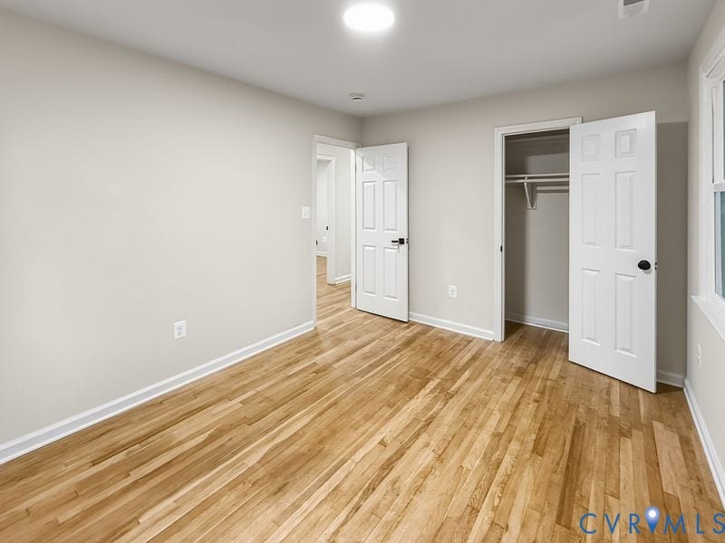 Recessed lighting, wood-finish flooring, white trim, and a window