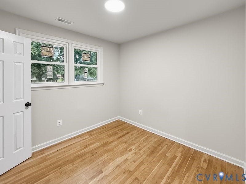 Hardwood flooring, neutral wall tones, white trim, and two windows