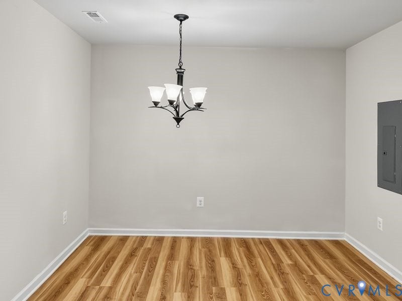 Wood-finish flooring, neutral wall tones, and a dark-toned chandelier