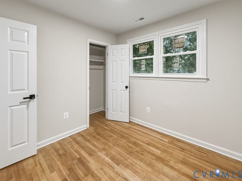 Wood-finish flooring, white walls, and a window with white trim