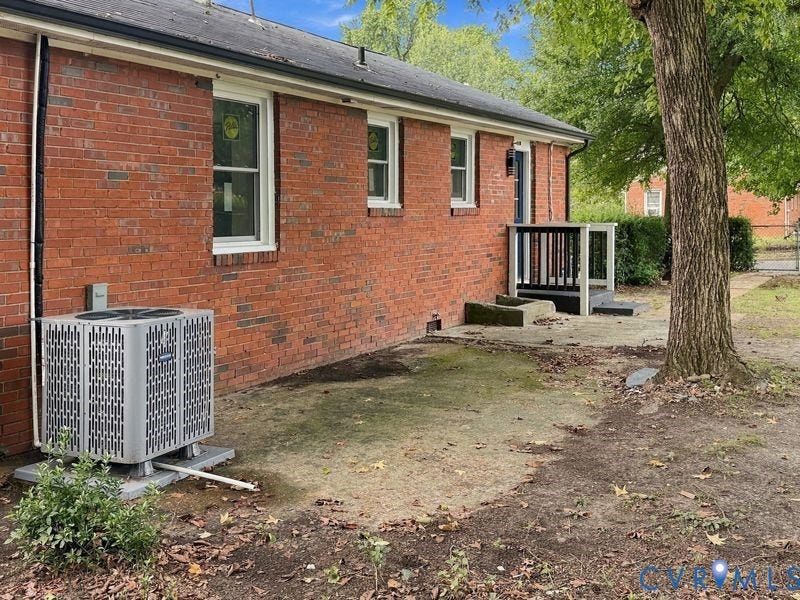 Brick exterior with white-framed windows, a rear entry with a small deck and railing, and an exterior HVAC unit