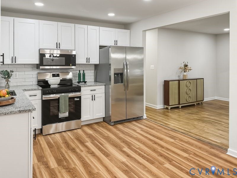 Contemporary kitchen featuring stainless steel appliances, white shaker cabinetry, and granite countertops