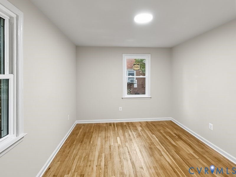 Wood-finish flooring with white trim, recessed ceiling lighting, and two windows