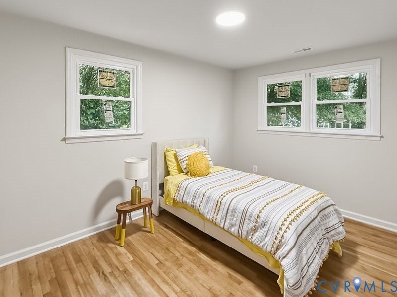 Recessed ceiling lighting, wood-finish flooring, two large windows, white trim, and light gray walls