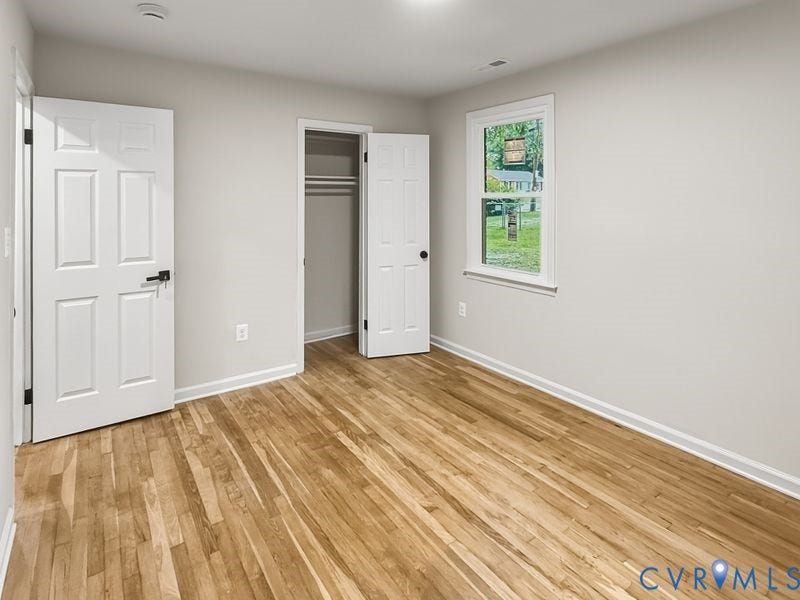 Wood-finish flooring, white paneled doors with matte black hardware, recessed lighting, and a window with white trim