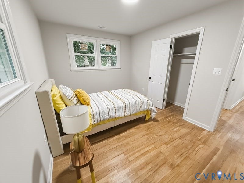 Light wood-finish flooring with white trim and a closet featuring a white paneled door