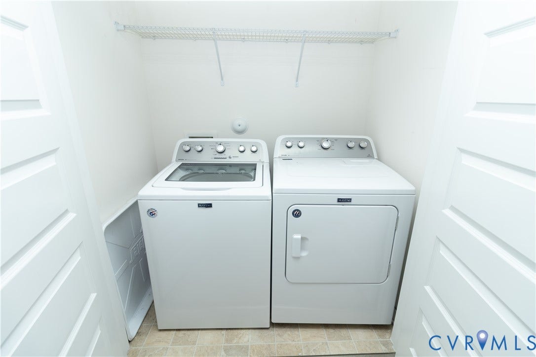 Dedicated laundry area featuring a white washing machine, white dryer, and a wire storage shelf