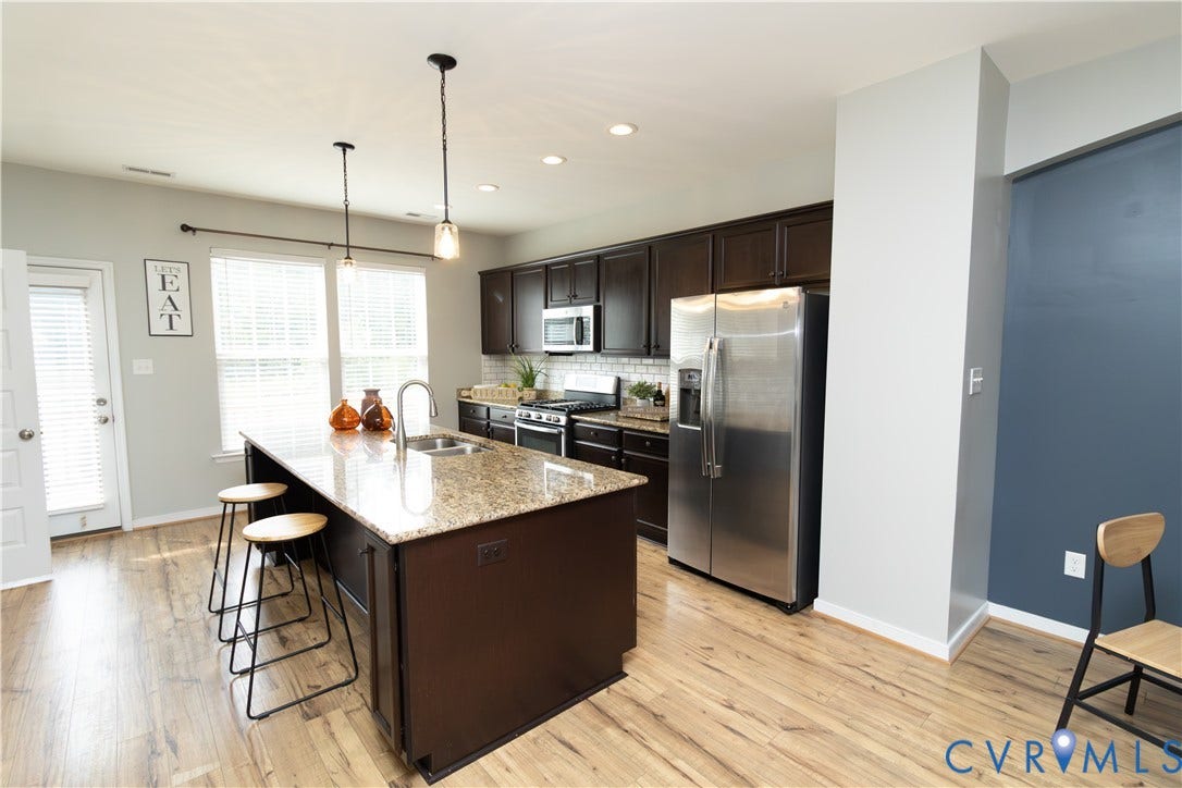 Kitchen with a center island featuring a granite countertop, dark wood-finish cabinetry, and stainless steel appliances