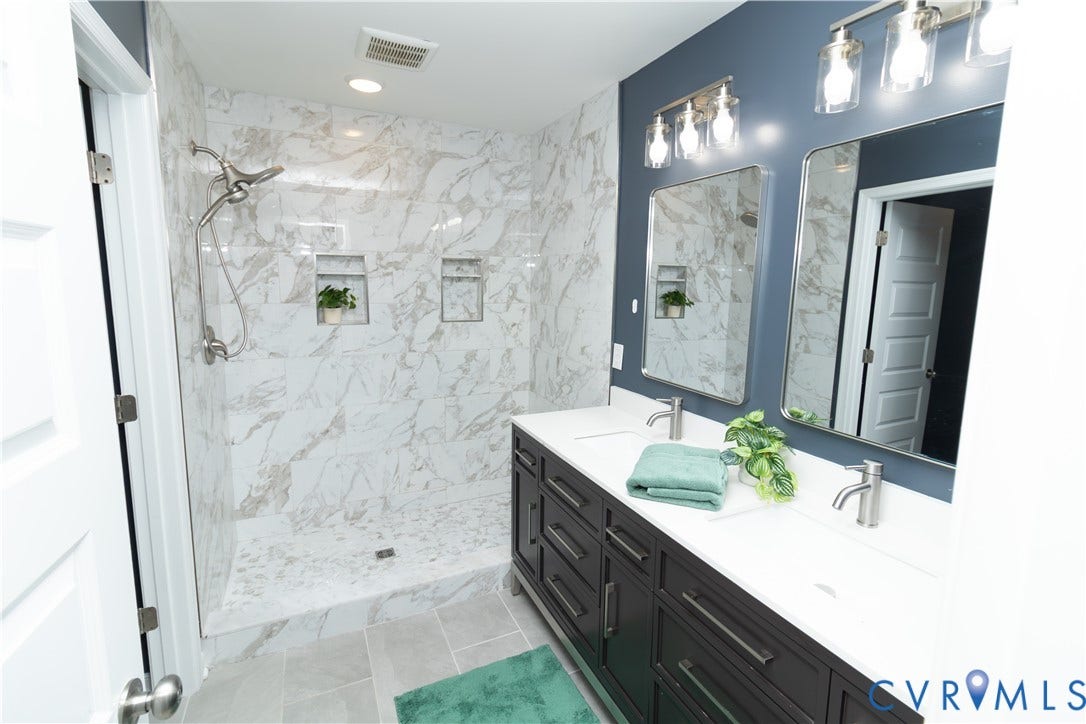 Walk-in shower with full wall and floor tile, dual recessed niches, and a glass enclosure