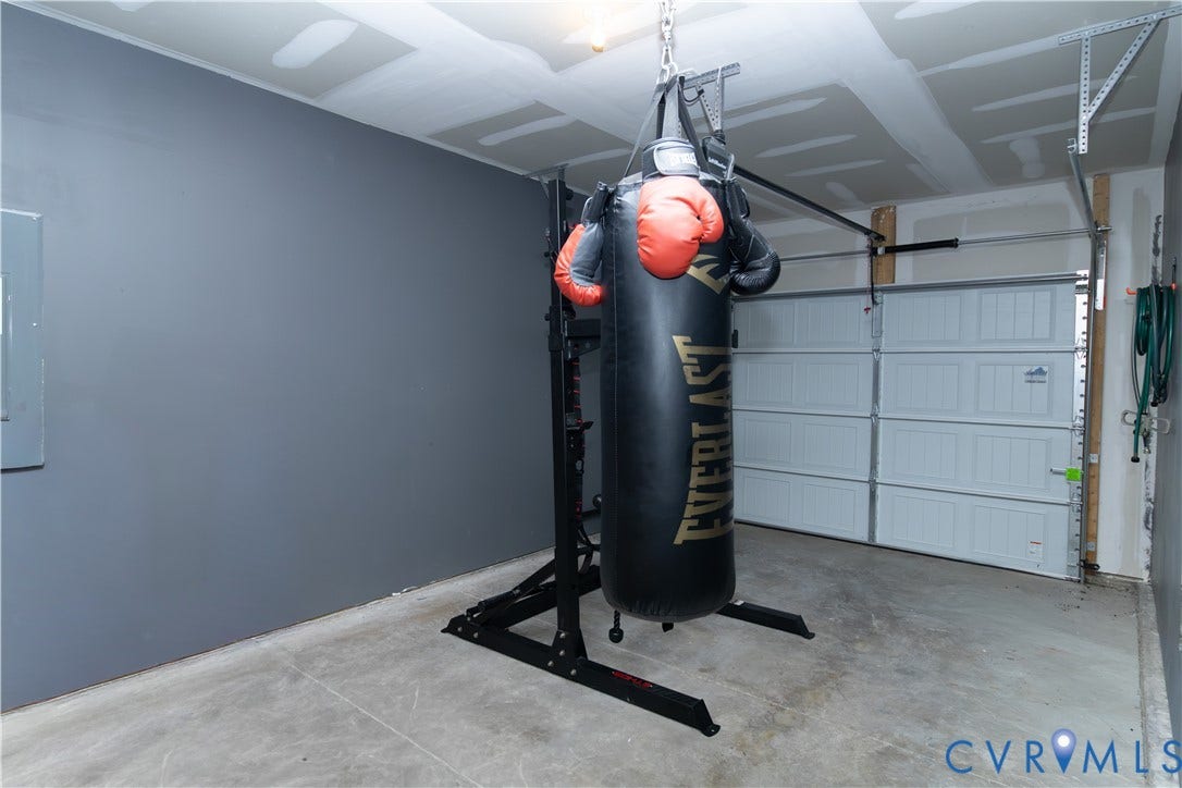 Finished garage with painted walls, exposed ceiling joists, and a concrete floor