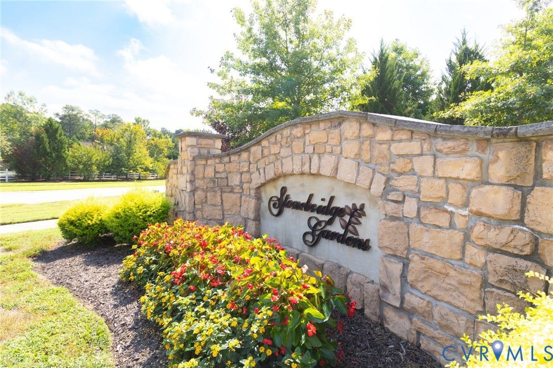 Stonebridge Gardens community entrance featuring a stone wall with integrated signage and decorative landscaping