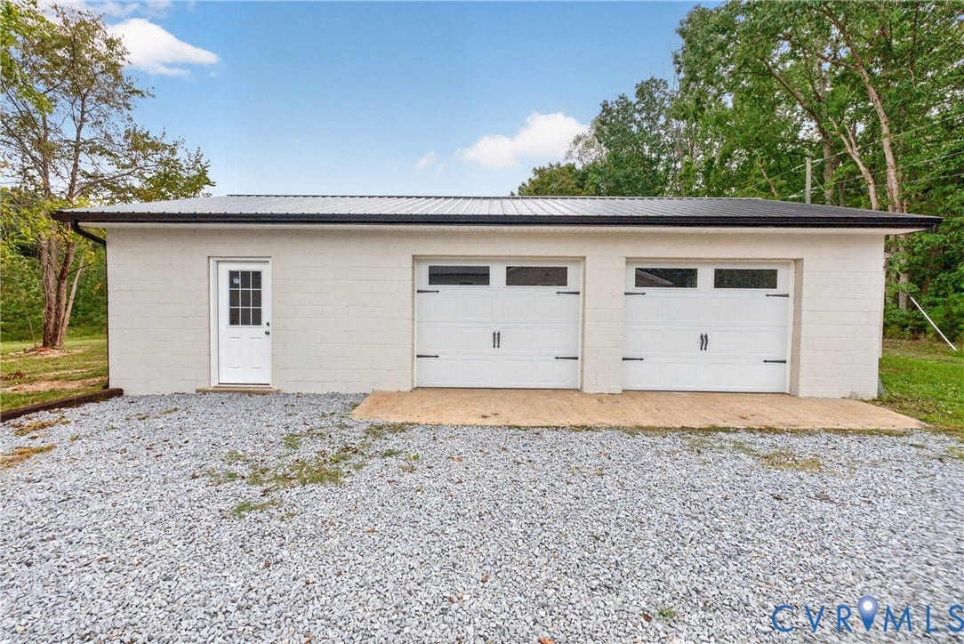 7621 Amelia Springs Road, Amelia, VA 23083 Detached garage with a metal roof, two overhead garage doors, a side entry door, and a gravel drive