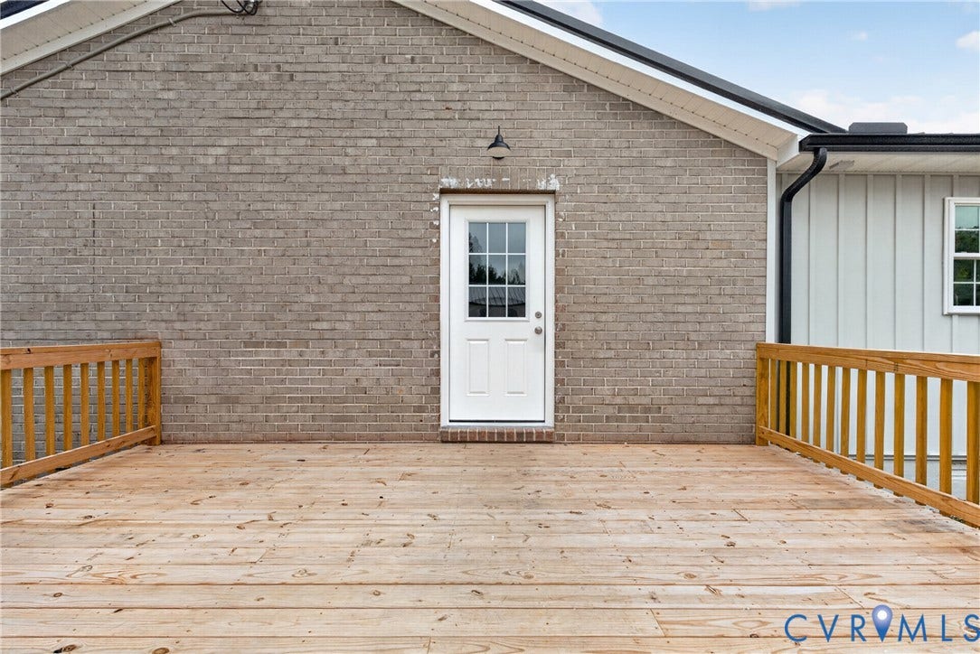 7621 Amelia Springs Road, Amelia, VA 23083 Expansive wood deck with a natural finish, featuring wood railings and a brick exterior wall