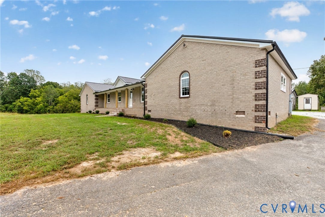 7621 Amelia Springs Road, Amelia, VA 23083 Brick exterior with contrasting brick corner accents, metal roof, arched window, and covered front porch with columns